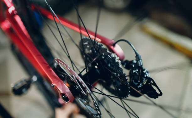 Mechanic repairman assembling custom bicycle in workshop rear view wheel