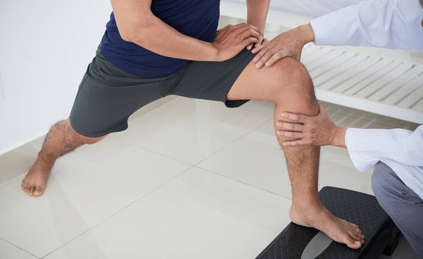 Cropped image of physiotherapist giving knee theraphy to young man